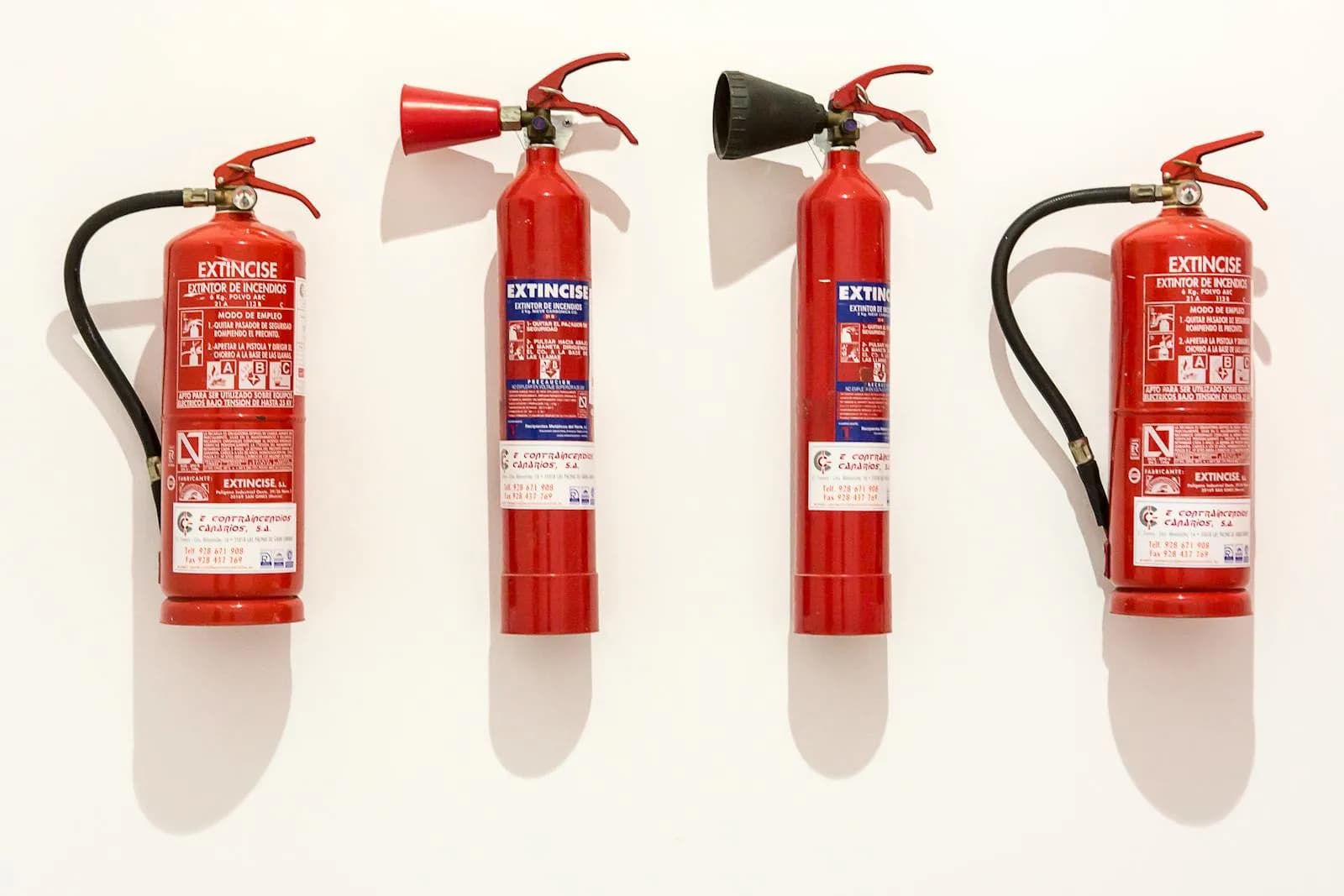 Quatre extincteurs rouges alignés, prêts à l'usage